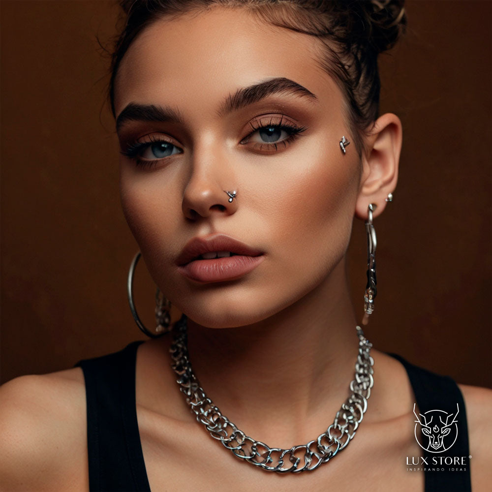 Modelo luciendo una variedad de piercings, incluyendo en la nariz, orejas y labios, con un estilo moderno y sofisticado. 